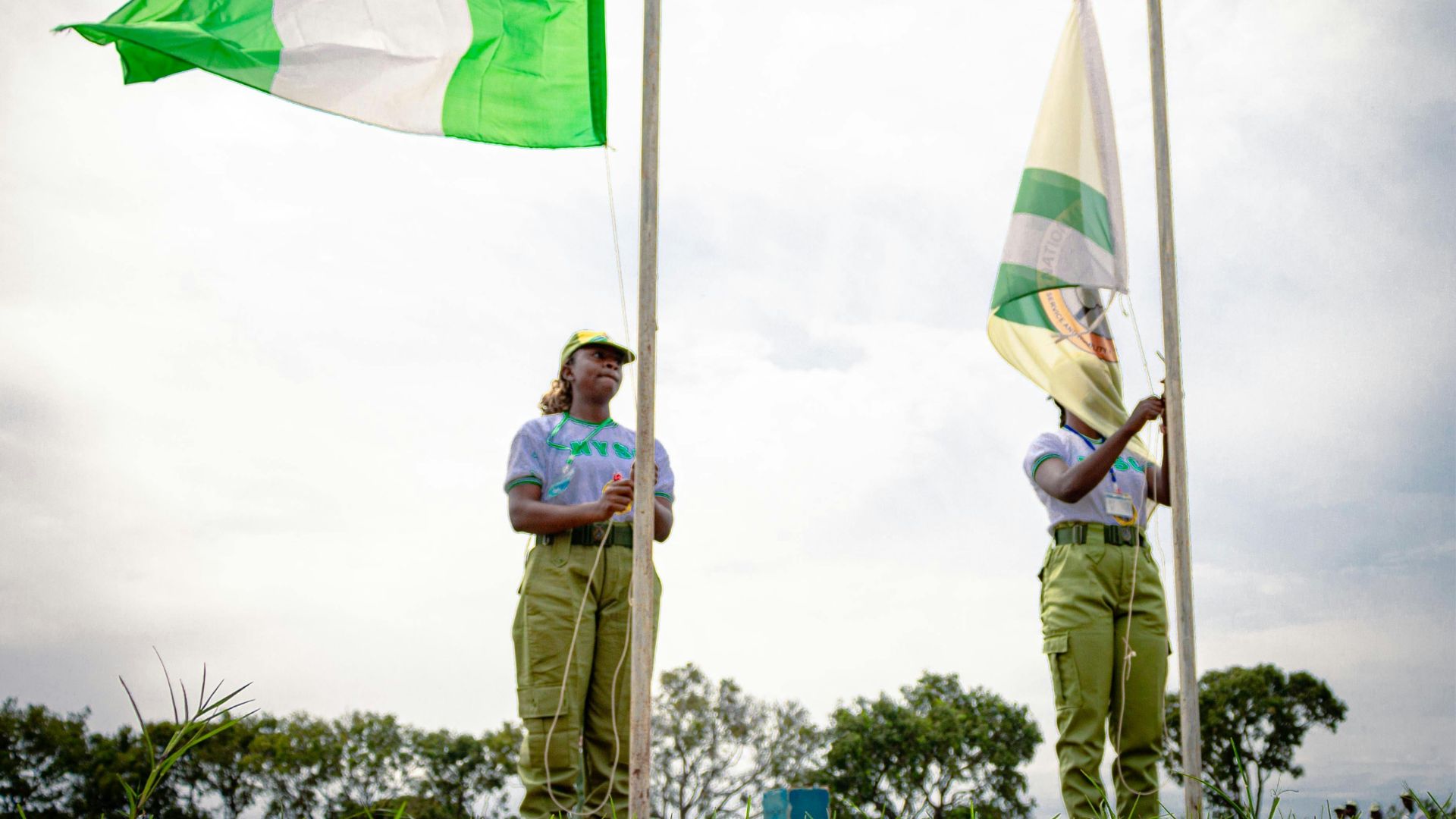 Nigerian NYSC Members Hoisting Flags Outdoors